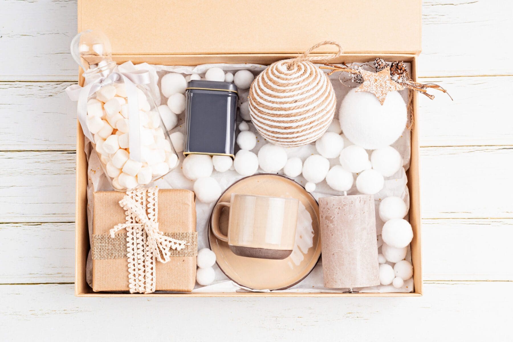 Preparing care package, seasonal gift box with tea, candle, cup and xmas ornaments. Personalized eco friendly basket for family and friends